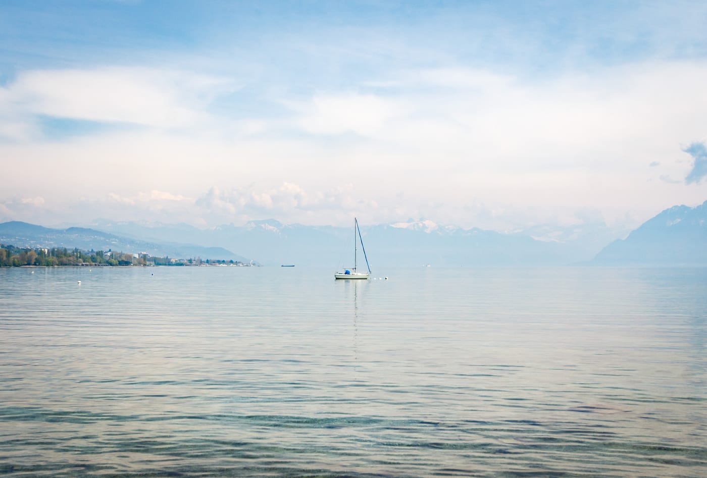 Lake Geneva from Lausanne in late April light. The Lake Geneva arc (Geneva, Vaud, Valais) absorbed 22 percent year-on-year growth in Swiss lump-sum permits in 2025, with British nationals 10 percent of applicants.