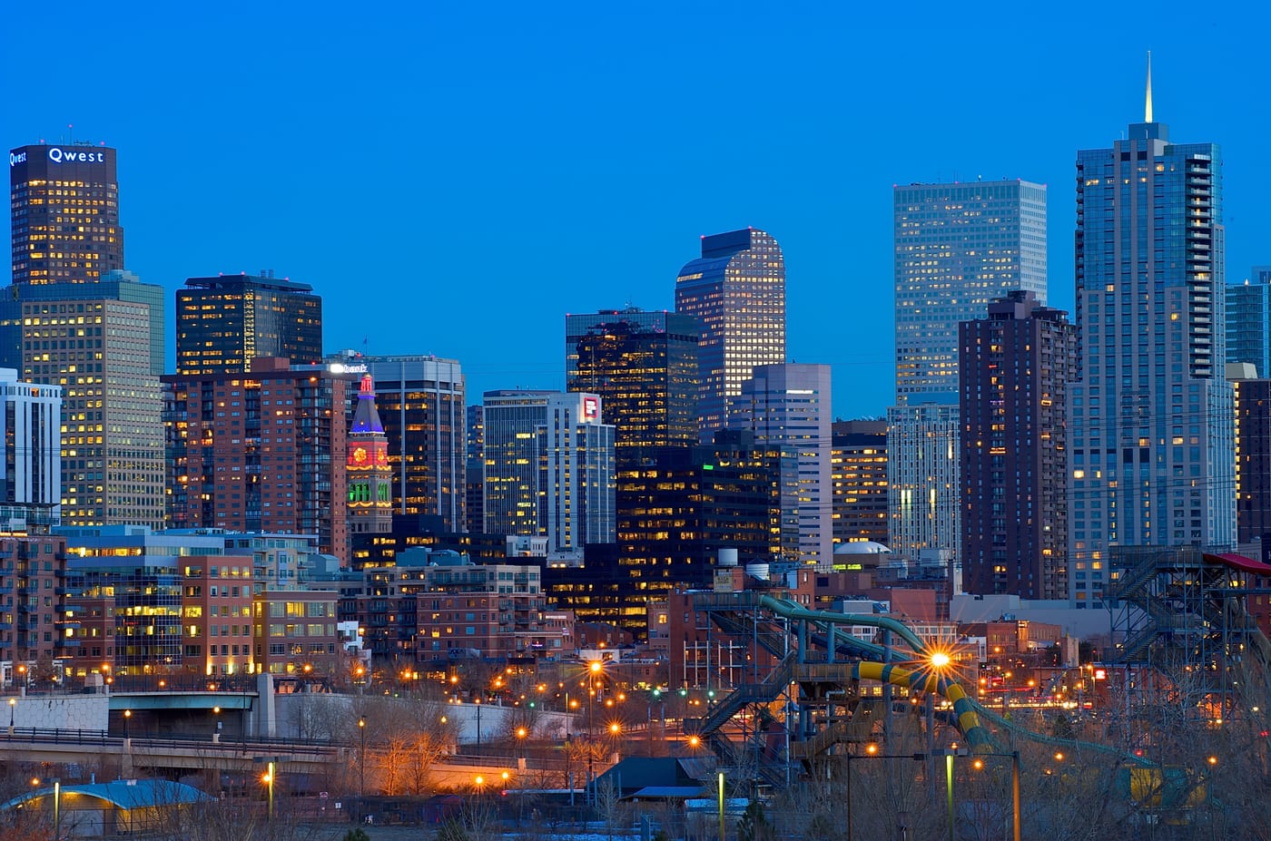 The Denver skyline. Denver is the operational base of the Walton-Penner Family Ownership Group's Denver Broncos NFL franchise (Rob Walton, August 2022, 4.65 billion dollars) and the Kroenke Sports and Entertainment Denver Nuggets (NBA) and Colorado Avalanche (NHL) franchises.